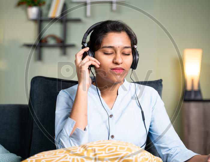 Young Girl Listening Peaceful Music At Home While Lying On Sofa After Coming From Office - Concept Of Music Lover, Lazy Weekend Relaxation And Modern Day Lifestyle
