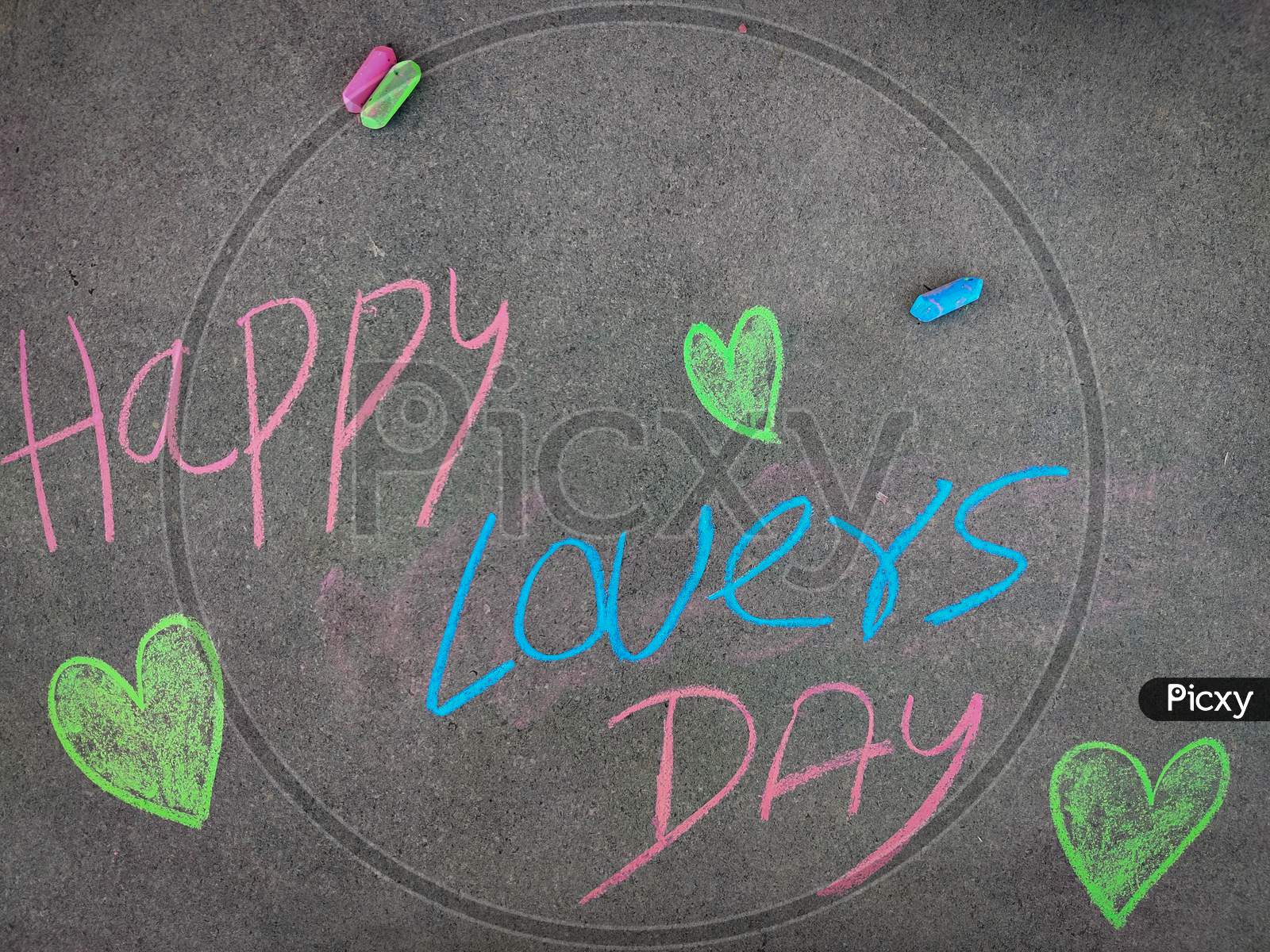 The Inscription Text On The Grey Board, Happy Lovers Day With Love Symbols. Using Color Chalk Pieces.