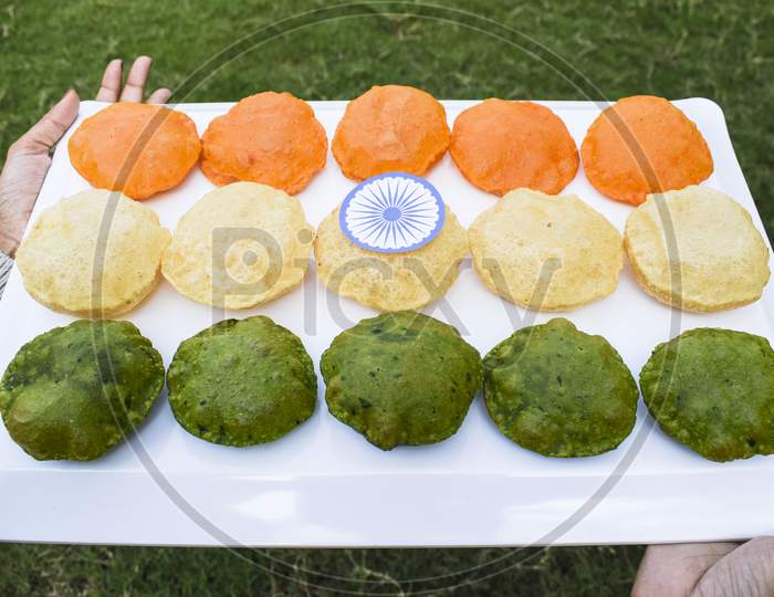 Female Holding Homemade Colourful Puris Made From Spinach, Carrot, On Occasion Of Indian Republic Day Holiday Representing Indain Tricolor Flag Of Saffron, White, Green Colors With Ashoka Chakra