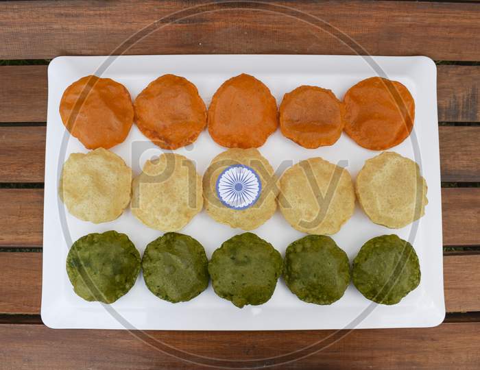 India Tricolor / Tricolour Food Breakfast Of Spinach Puri, Carrot Puri, And Plain Puri. Concept For Indian Republic Day Celebration On 26 January With Ashoka Chakra.