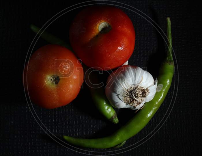 Green Chilly, Garlic, Tomato, Onion And Curry Leaf Are Isolated On Black Background. Ingredients Concept. Hot And Spicy Green Chillies And Fresh Ripe Tomato, Onion On Black Background.