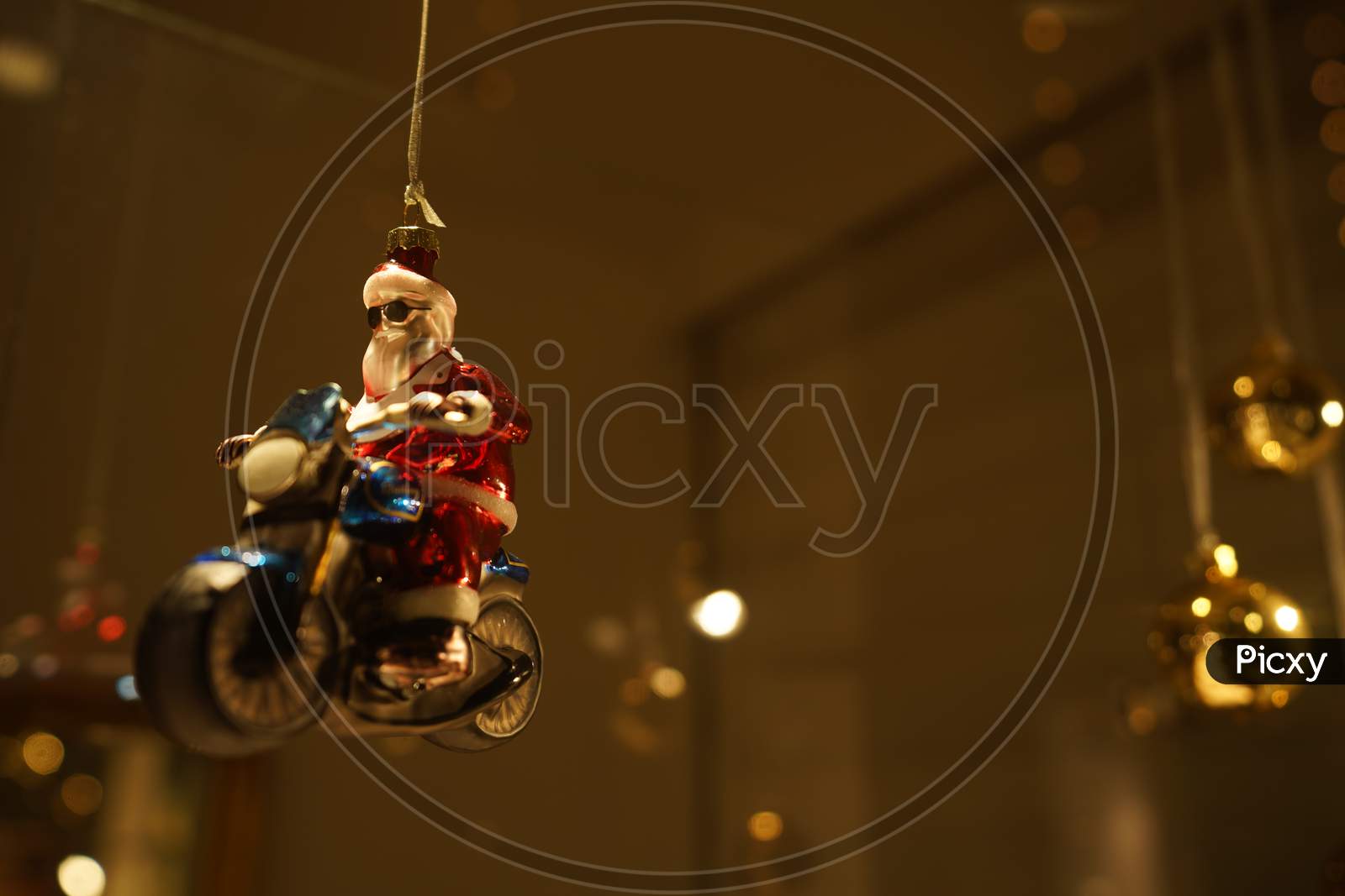 Close-Up Of Santa Clause Bauble On Motorcycle. Retro And Vintage Decoration In Illuminated Showcase In Dark Evening.