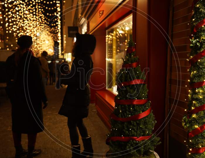 Pedestrians Standing In Front Of A Luxury Store Window In Dark Evening. Christmas Window Shopping In Zurich.