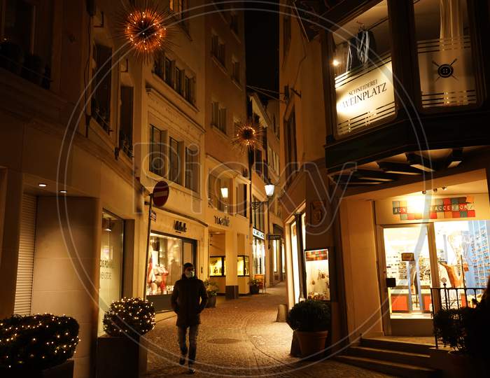 Pedestrians Walking In Front Of A Luxury Store Window In Dark Evening. Christmas Window Shopping In Side Streets Of Bahnhofstrasse In Zurich.