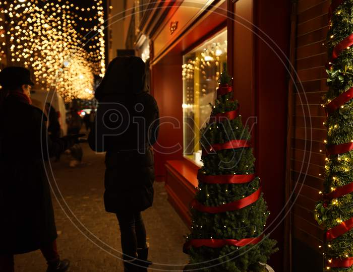Pedestrians Standing In Front Of A Luxury Store Window In Dark Evening. Christmas Window Shopping In Zurich.