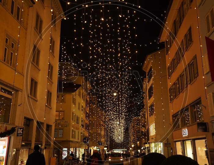 Christmas Shopping, Pedestrian Under Traditional Christmas Lights Lucy In Side Street Rennweg In Zurich.