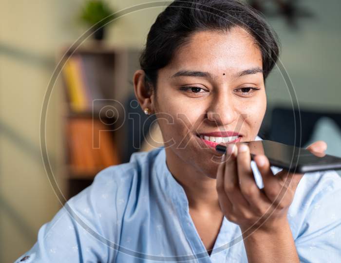Close Up Shot Of Happy Smiling Young Business Woman Talking On Spaker Of Mobile Phone At Workplace During Office Hours.