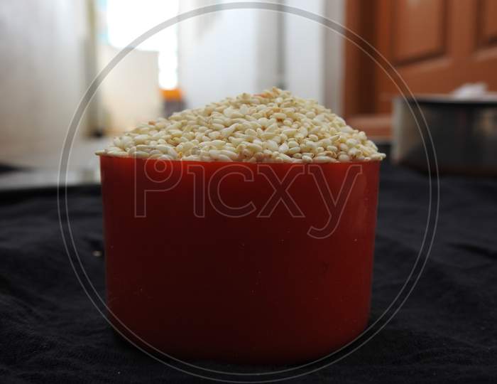 White color Sesame Seeds in a Traditional Sand Bowl and Plastic Cup isolated on black background