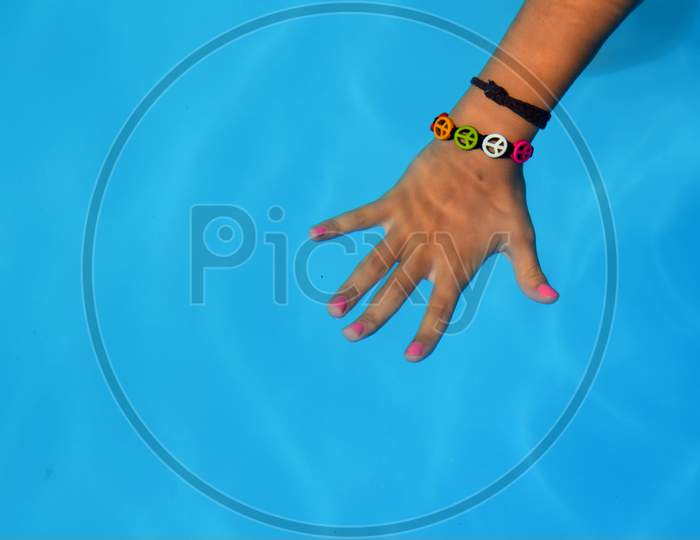 A Hand Under The Blue Water Of A Swimming Pool