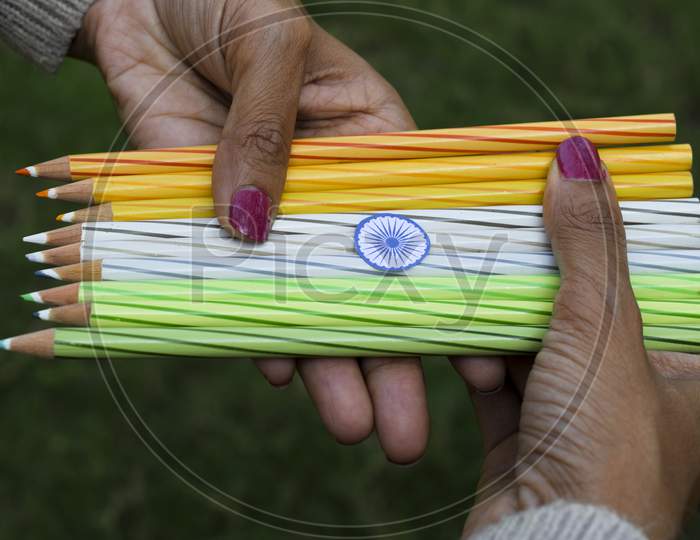 Indian Flag Tricolor Tiranga Orange, White And Green Colour Pencils. Female Palms Holding Embroidered Thread As Concept For Indian Republic Day Celebration Depicting Concept Of Freedom