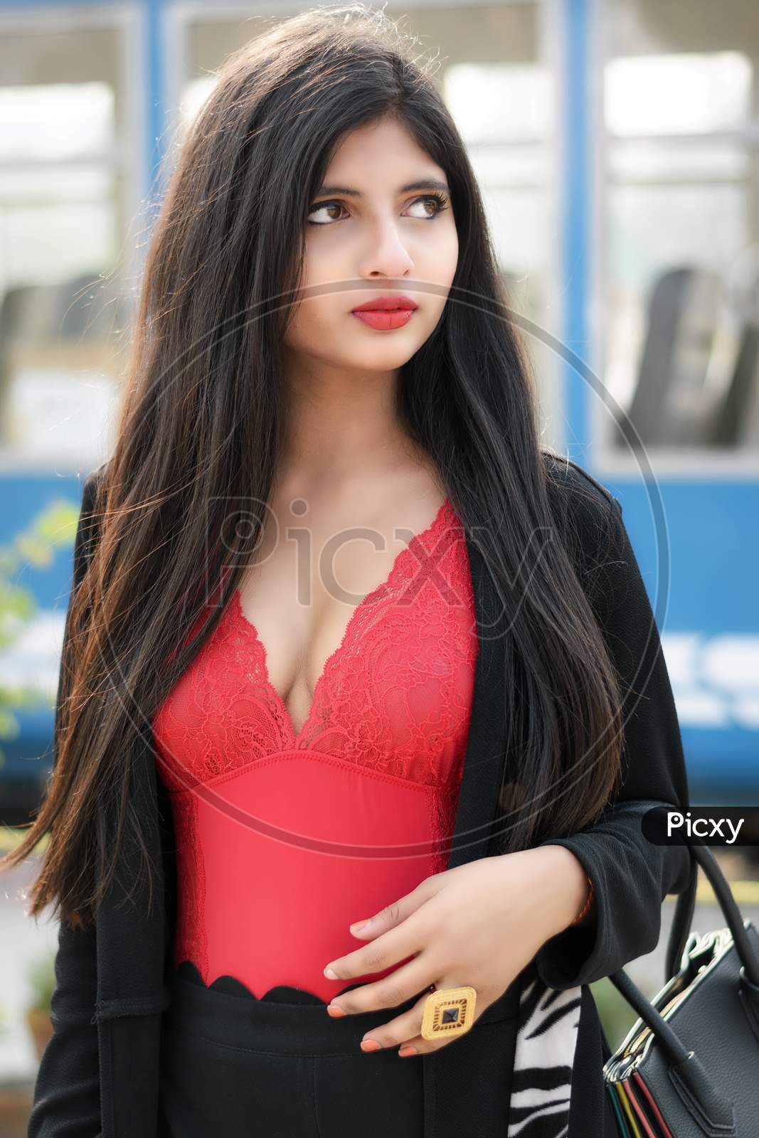 Portrait Of Very Beautiful Straight Haired Young Attractive Indian Woman Wearing Red Outfit With Black Jacket Posing Fashionable In A Blurred Background. Lifestyle And Fashion.