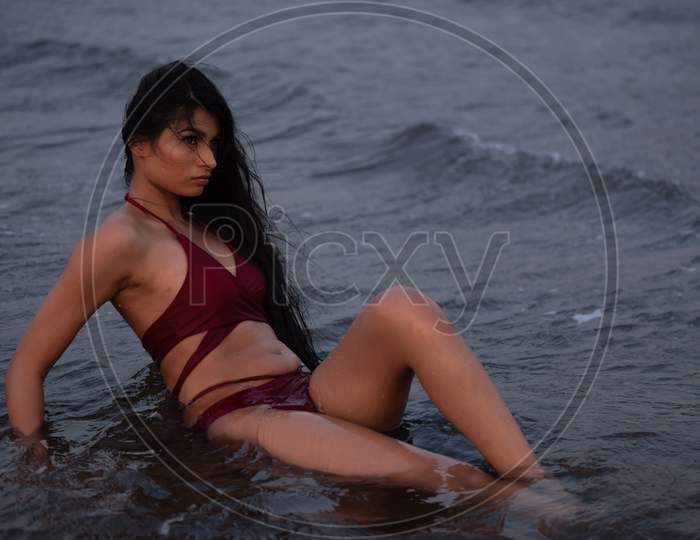 Young Indian girl in red bikini enjoying her vacation on beach and relaxing on beach