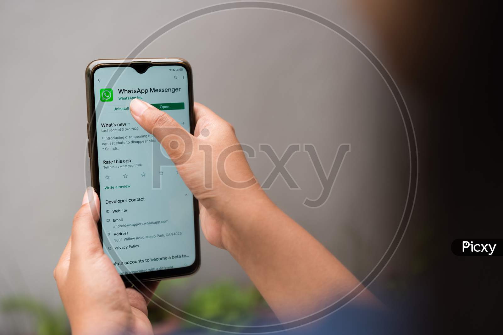 Over the shoulder photo of a person uninstalling Whatsapp on a smartphone. Quitting social media apps for self improvement, time management, privacy