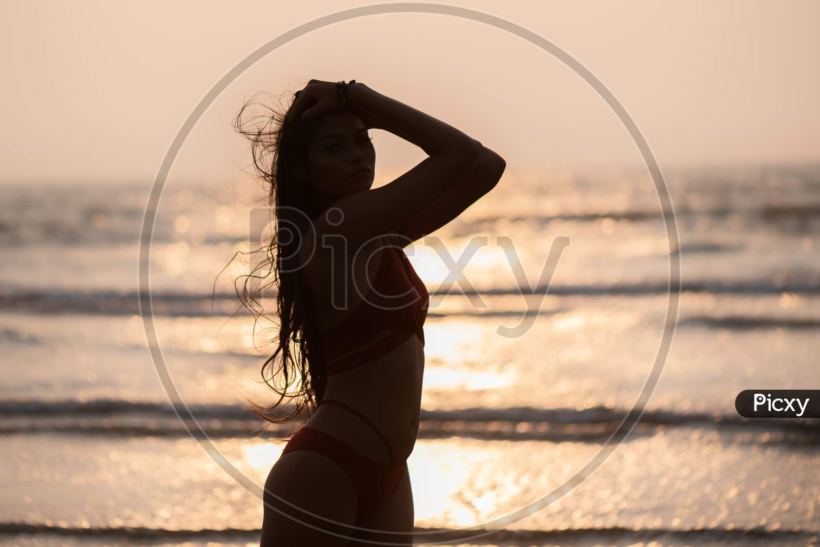 Image of Silhouette of young India girl in red bikini enjoying her