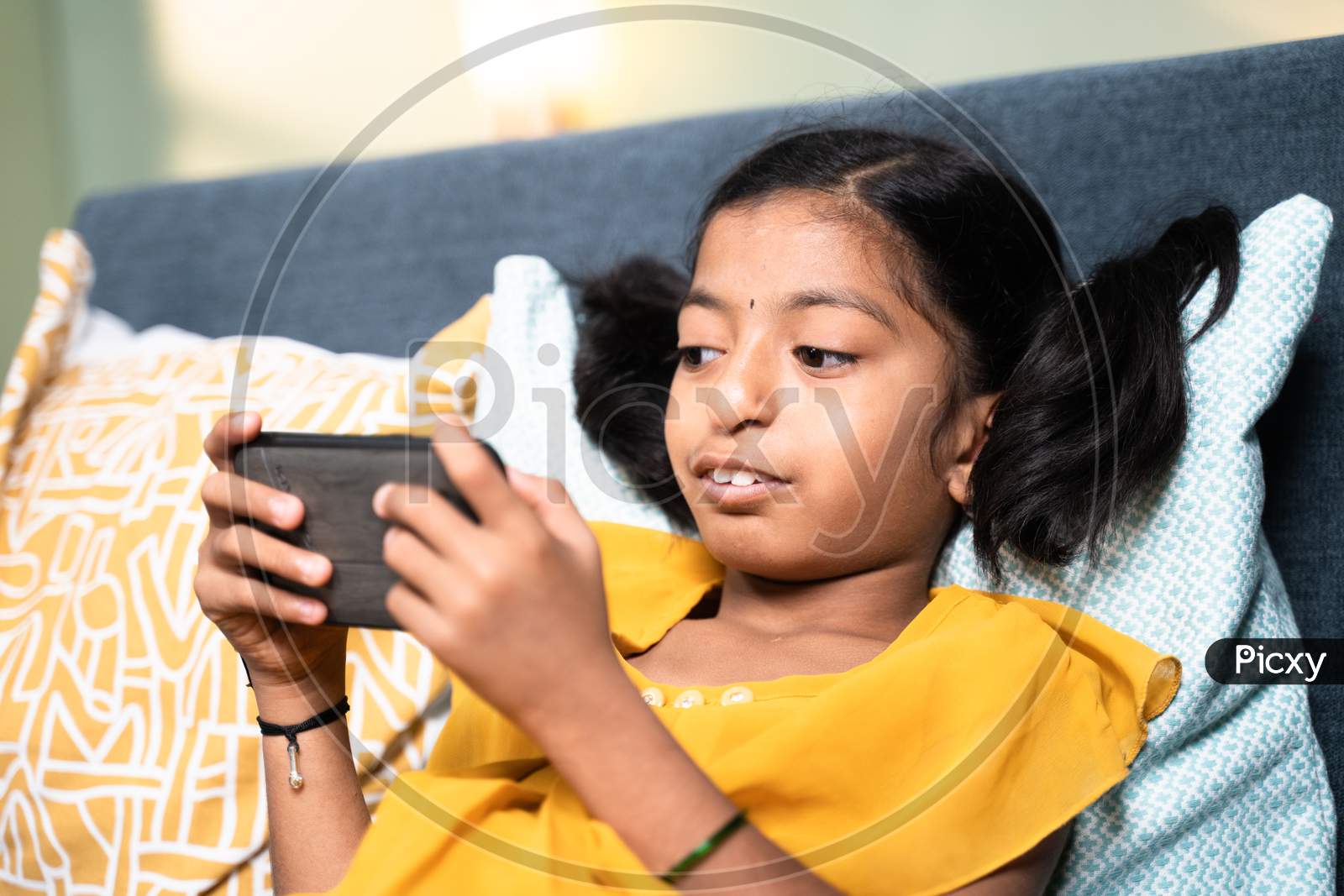 Young Girl Disabled Kid Using Mobile Phone While Sleeping On Sofa - Concept Of Kid Mobile Phone Game Addiction, Technology And Modern Lifestyle.
