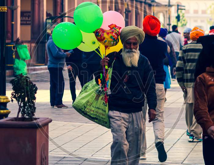 an old man selling balloons walking on the street