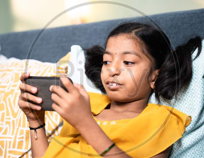 Young Girl Disabled Kid Using Mobile Phone While Sleeping On Sofa - Concept Of Kid Mobile Phone Game Addiction, Technology And Modern Lifestyle.
