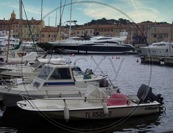 Saint Tropez, France - May 04th 2018: A german photographer visiting the french riviera, taking pictures of the contrast between the exclusive yachts and the small wooden fisher boats.