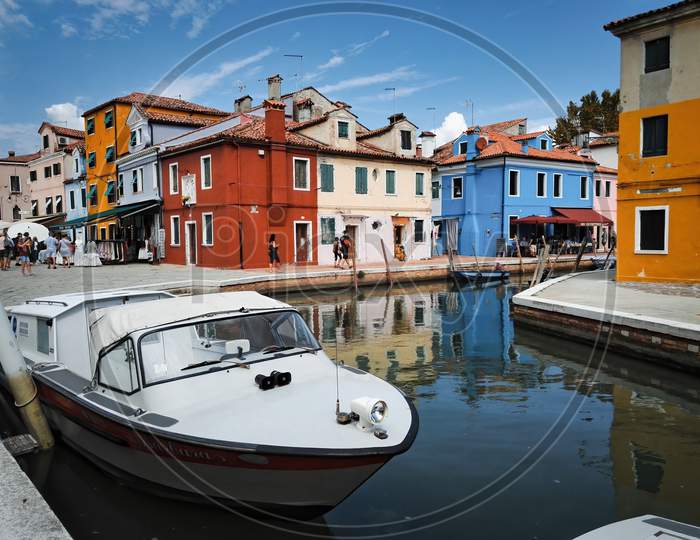 Venice, Italy - September 03, 2018: Wide Angle Shot Of A White Jet Boat Against Colorful Building Architecture Located In Burano Island