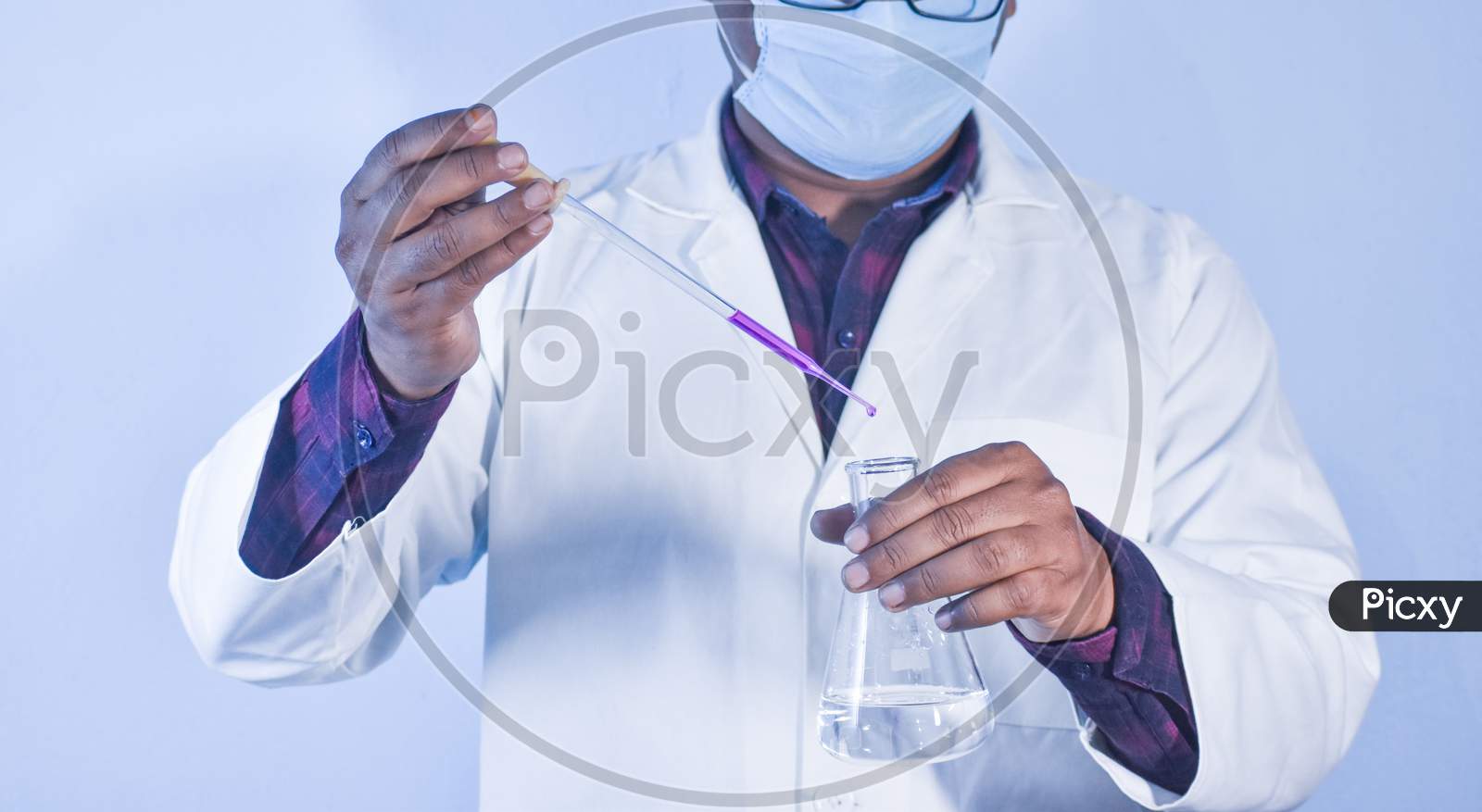 Scientist Pouring Color Liquid Into A Conical Flask With A Dropper In Chemistry Laboratory