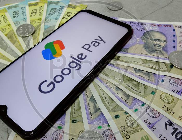 Tamil Nadu, India - January 21 2021: Indian currency notes along with new logo of Google pay on a smart phone