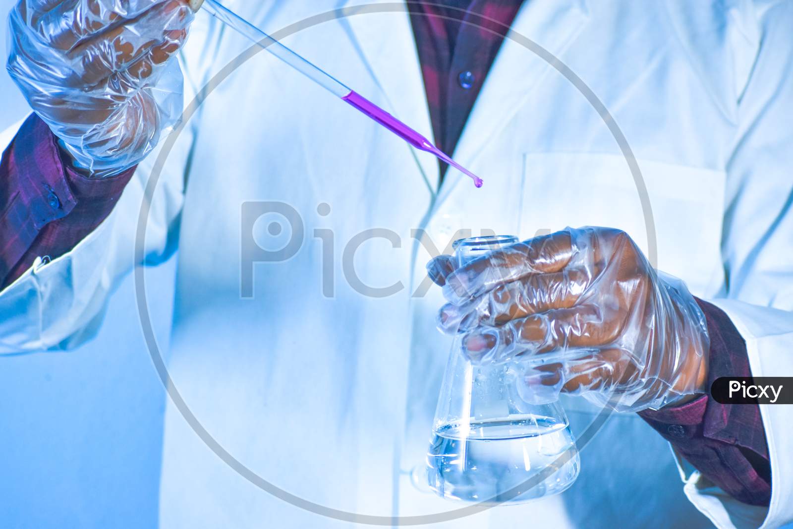 Scientist Pouring Color Liquid Into A Conical Flask With A Dropper