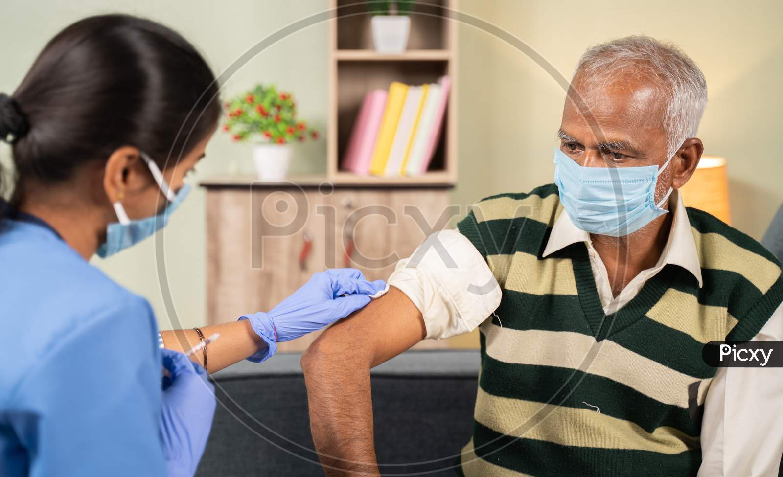 Doctor Preparing Vaccination Shot To Elderly Patient By Holding Syringe At Home - Concept Of Home Health Check To Seniors During Coronavirus Covid-19 Vaccine Immunization.