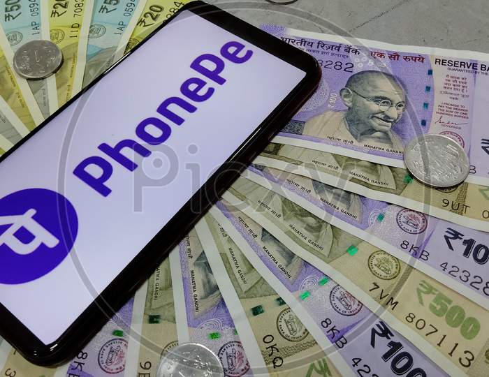 Tamil Nadu, India - January 21 2021: Indian currency notes along with logo of PhonePe on a smart phone
