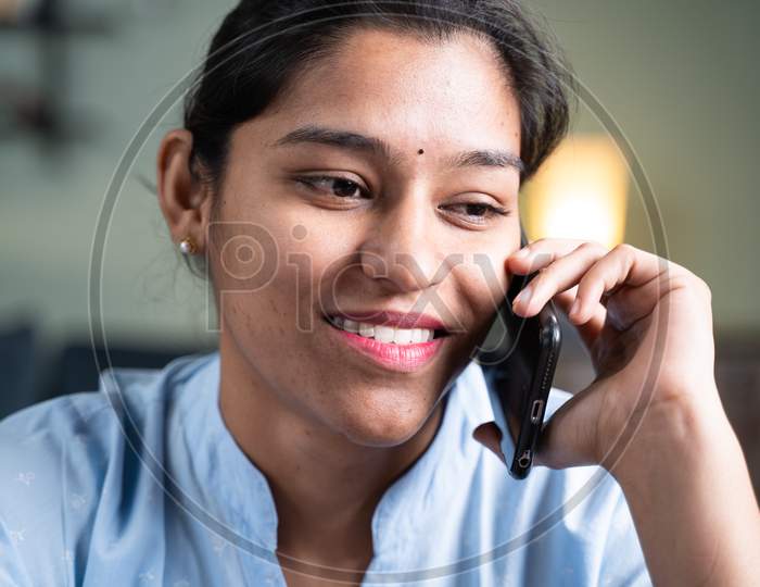 Close Up Head Shot Of Happy Smiling Young Indian Business Woman Busy Talking Or Having Conversation On Mobile Phone Call - Concept Of Positive Mood Or Emotion Or Doing Doing Time Pass At Work Place