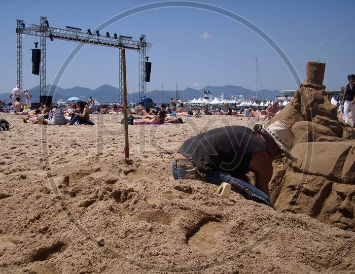Cannes, France - 07th May 2018: A german photographer visiting the french riviera, exploring an outdoor artist who is making art made from sand next to some installations for the film festival.
