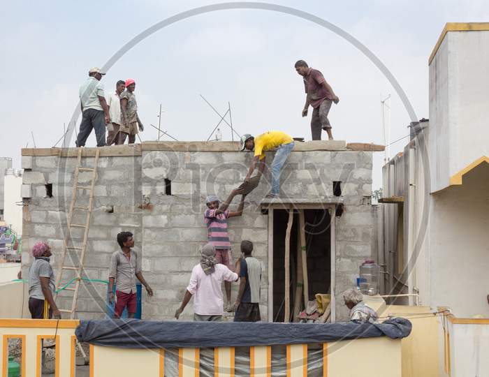A Midday picture of the Team work of poor Masons seen laying the Concrete roofing at a House construction site in Mysuru,India.