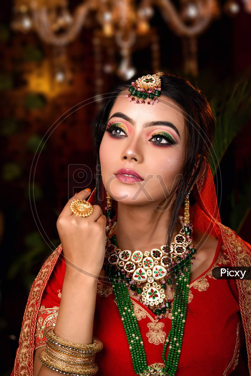Close Up Portrait Of Very Beautiful Young Indian Bride In Luxurious Bridal Costume With Makeup And Heavy Jewellery In Studio Lighting Indoor. Wedding Fashion.