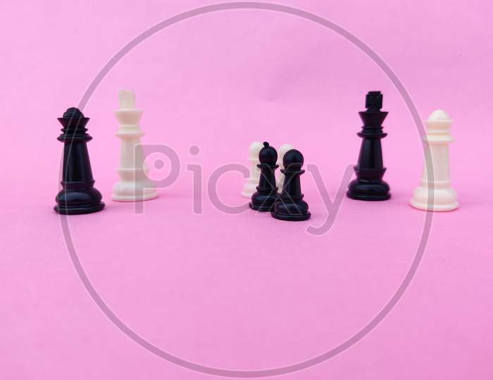Black And White Chess King,Queen Separated By Black And White Pawns. Isolated On Pink Background.