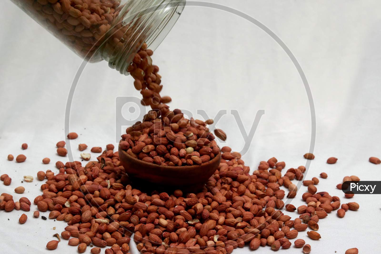 Raw Groundnuts in an earthen bowl on white background. Peanuts isolated. Top angle peanuts bowl. Peanut isolated. Raw peanuts bowl.