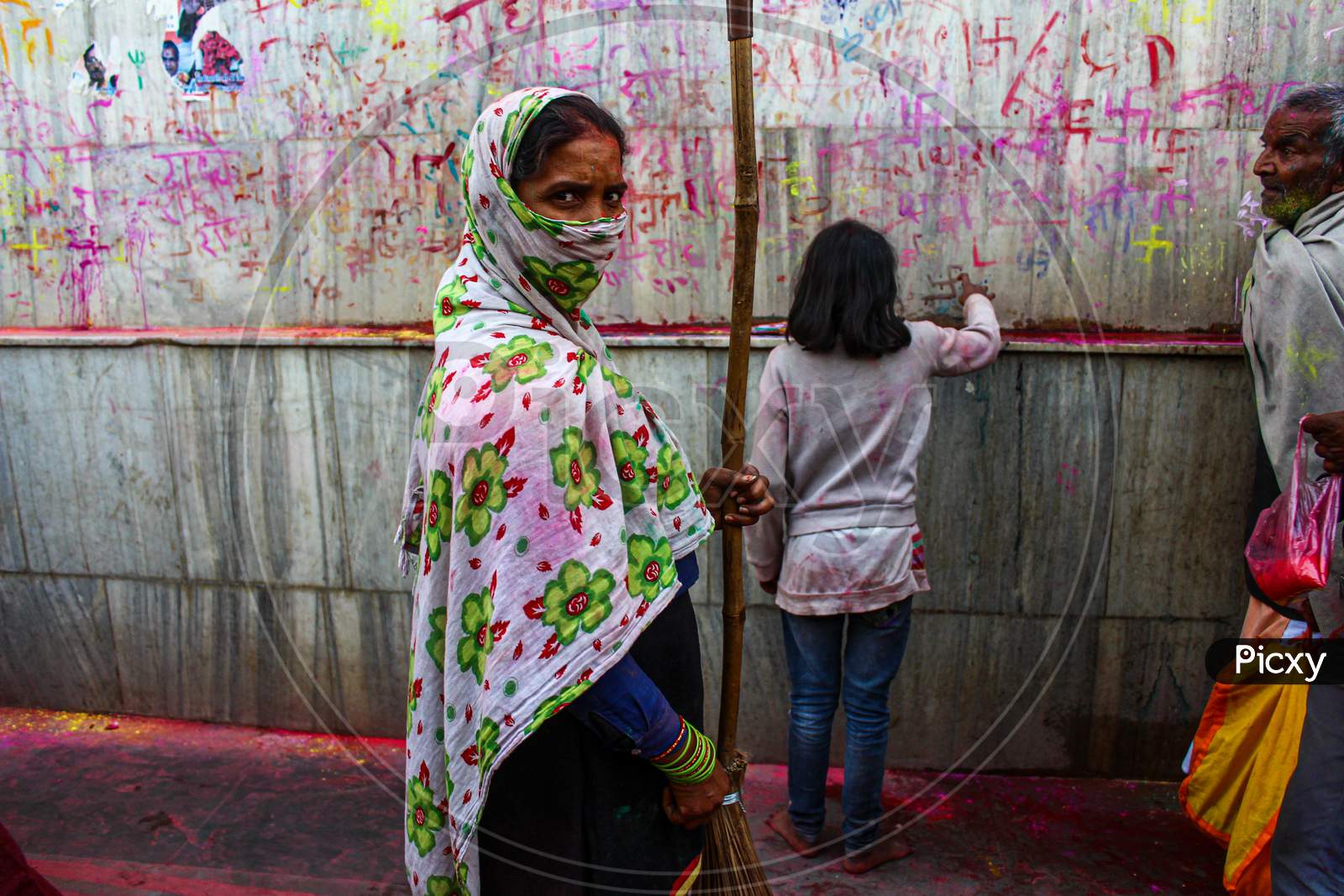 Mathura, Uttar Pradesh, India- January 6 2020: A Female Worker With Her Face Covered With A Cloth Cleaning The Temple Of Nandgaon During The Celebration Of Holi.