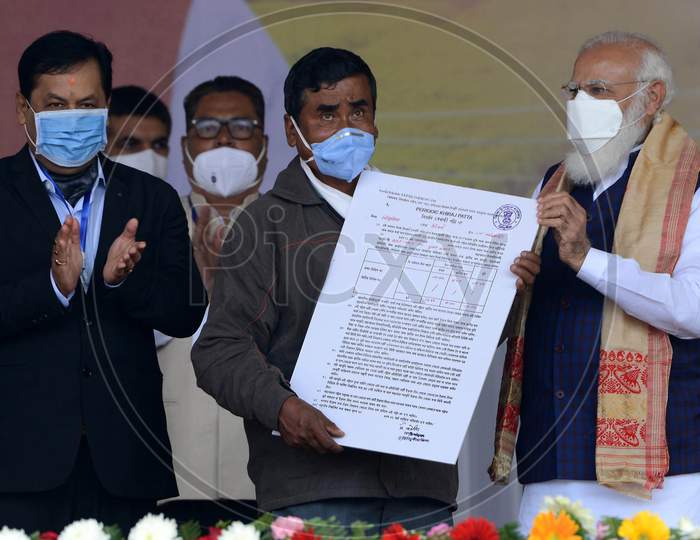 Prime Minister Narendra Modi distributes 'Land Patta' to a woman during a public meeting, at Jerenga Pathar in Sivasagar District of Assam on Jan 23,2021