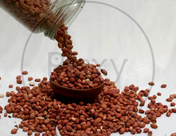 Raw Groundnuts in an earthen bowl on white background. Peanuts isolated. Top angle peanuts bowl. Peanut isolated. Raw peanuts bowl.