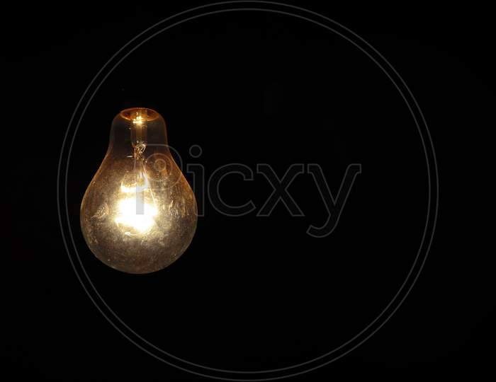 Old Glowing Light Bulb On Black Background
