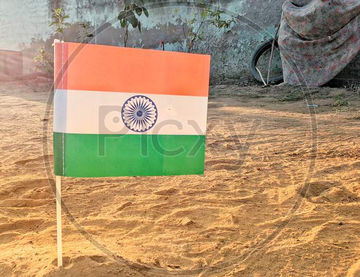 Official Flag Of Indian Government Closeup View With Plastic Flagpole Standing On The Ground. Tricolor Flag Or Tringa View.