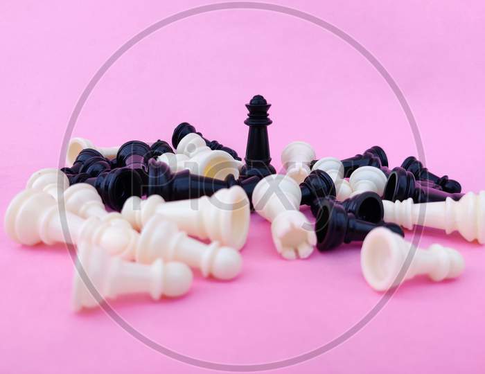 Black Chess Queen Surrounded By Number Of Fallen Chess Pieces. Pink Background. Business Concept