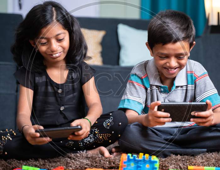 Two Young Sibling Kids Playing Online Video Game On Mobile Phone At Home - Concept Of Smartphone Game Addiction. Holidays, Modern Technology Lifestyle.