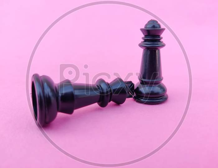 Black Chess King Surrender To Black Chess Queen Or Death Of A King, Queen Dominating The King Standing Above. Pink Background