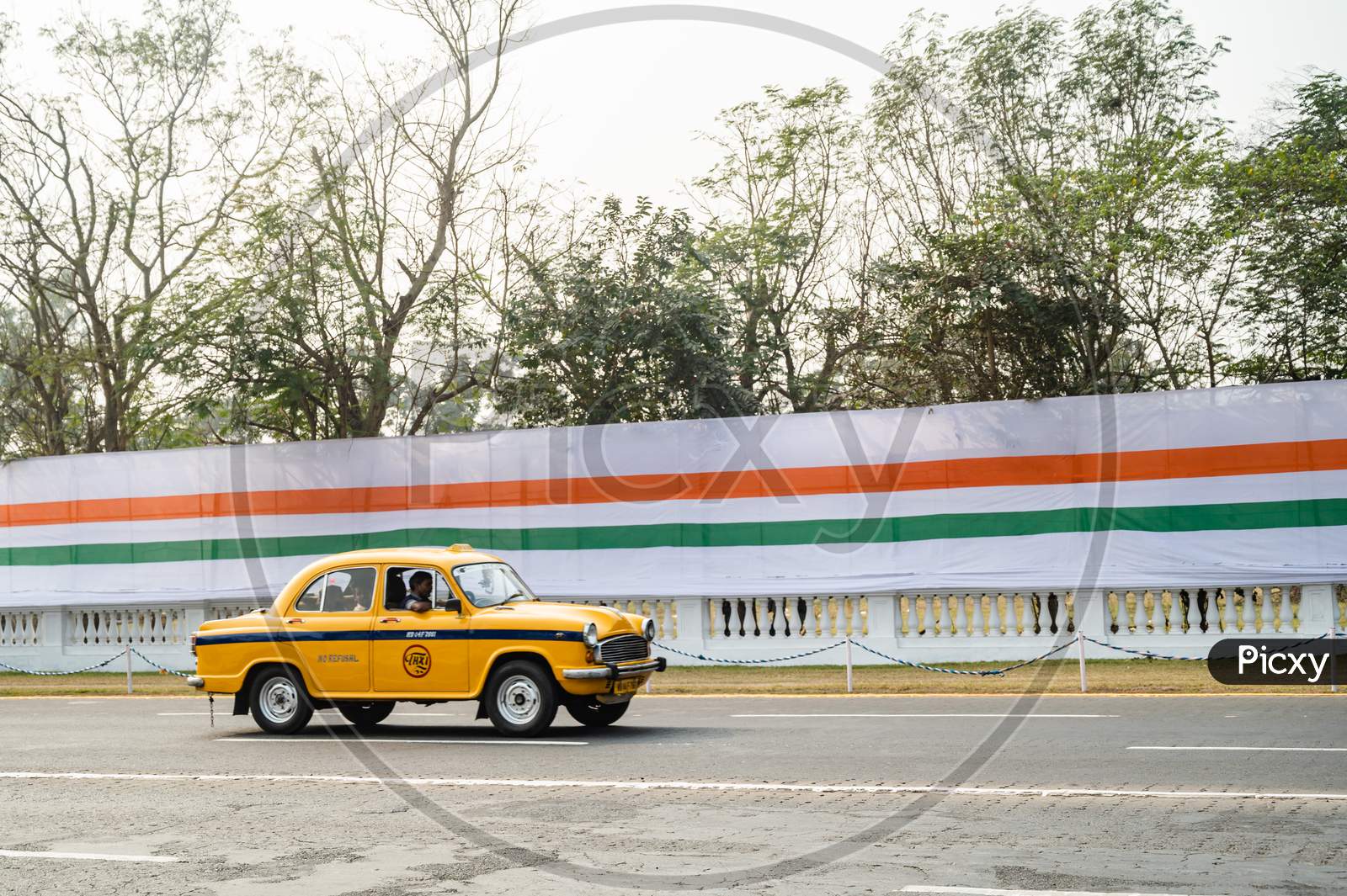 Yellow taxi passing on road in front of tricolor flag in Kolkata city after republic day parade. Indian tricolor flag.
