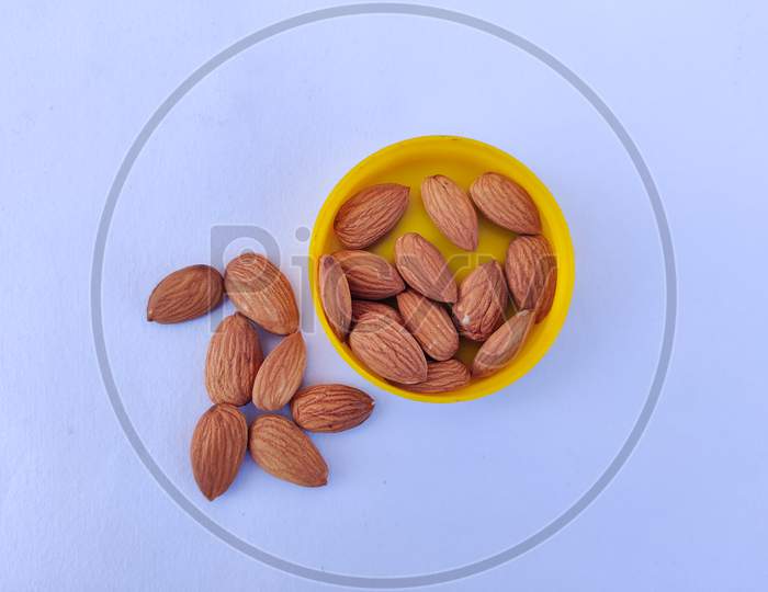 Top View Of Almonds In Yellow Plate. Isolated On White Background.