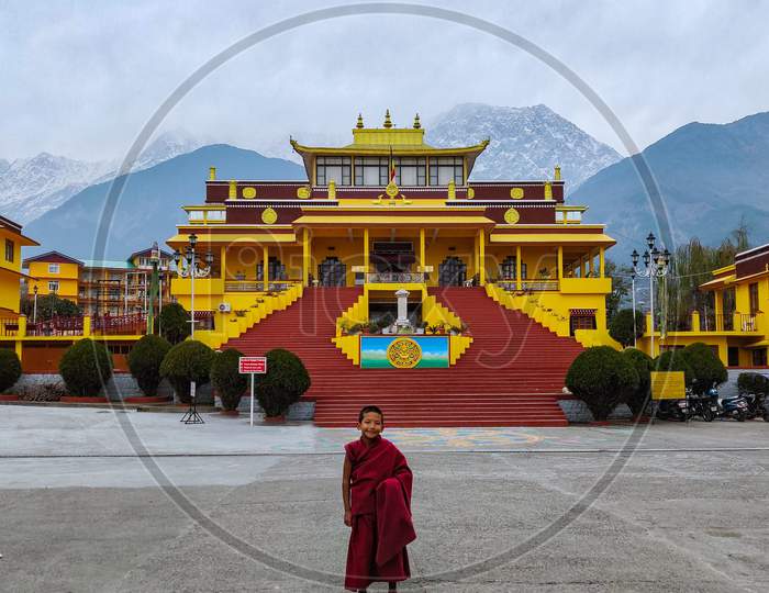 A young monk by a serene monastery by the mountains