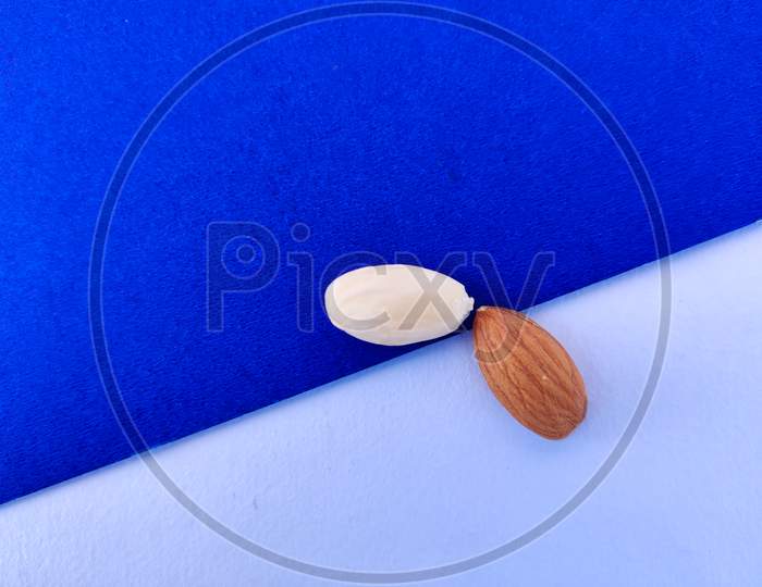 Peeled And Unpeeled Almonds Isolated On Blue And White Background.