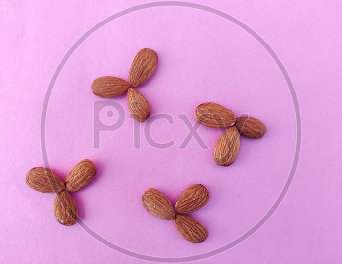 Collection Of Almonds Placed Like Flower Shaped. Isolated On Pink Background.
