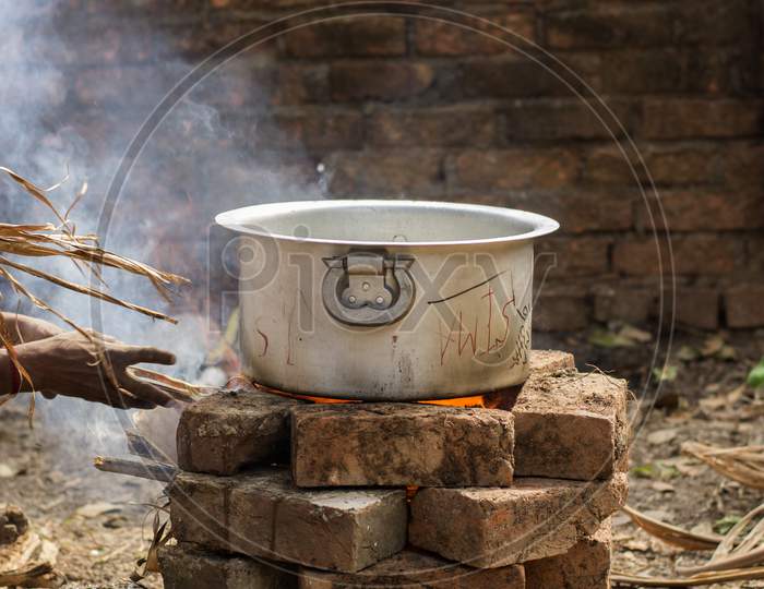 An Aluminum Utensil On A Temporarily Made Fire Oven By Bricks.
