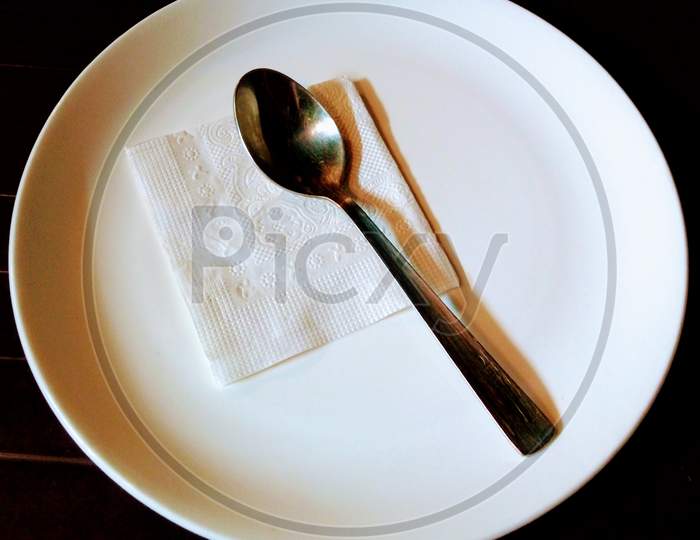 Empty white plate with spoon in a restaurant