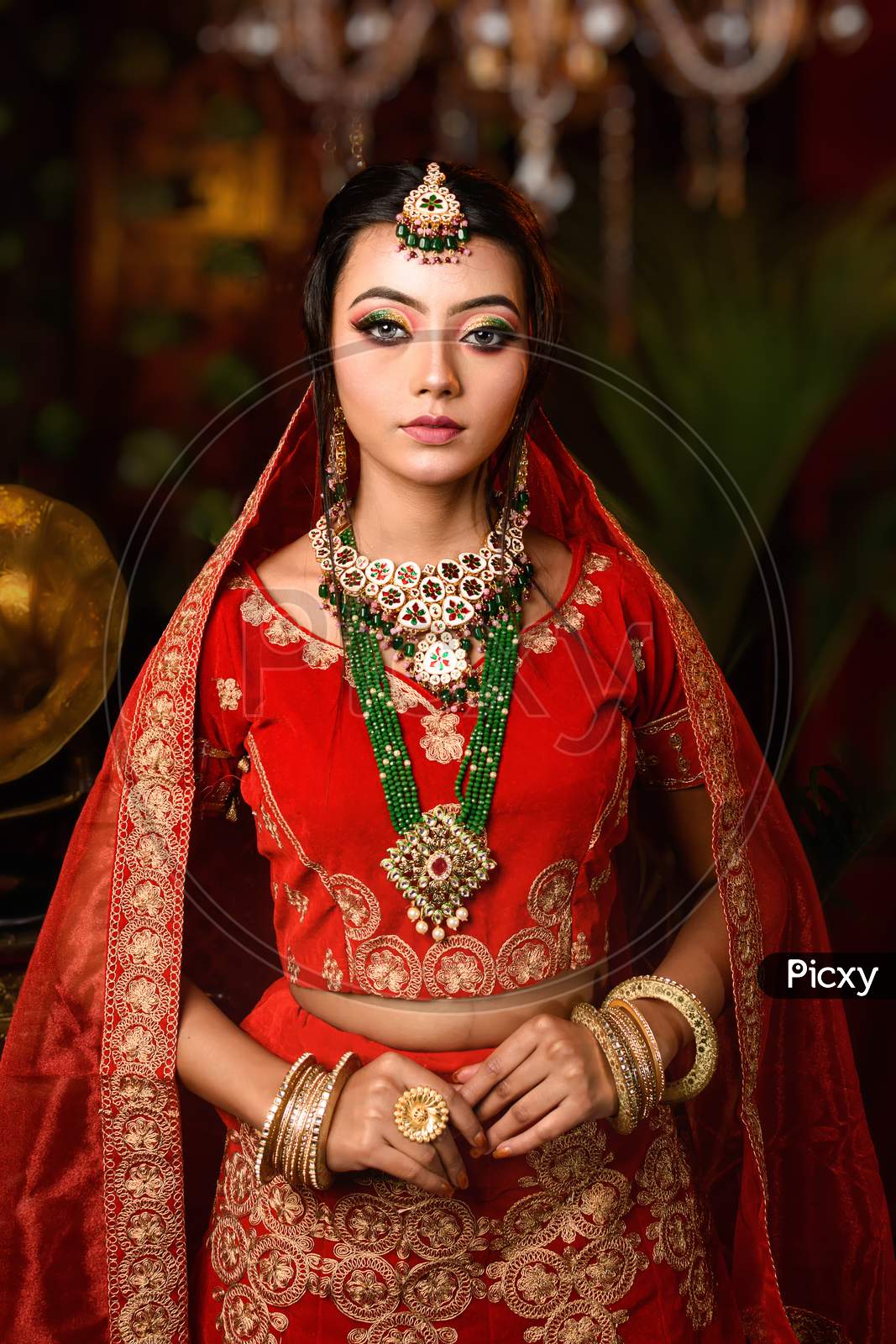 Magnificent Young Indian Bride In Luxurious Bridal Costume With Makeup And Heavy Jewellery With Classic Vintage Interior In Studio Lighting. Wedding Lifestyle And Fashion